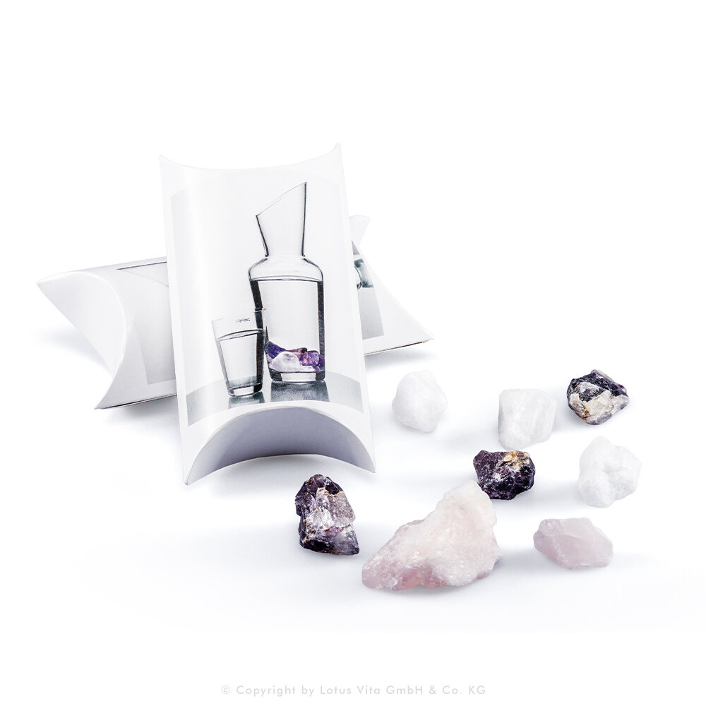 Naturbelassene Kristalle wie Rosenquarz und Amethyst zur Wasserenergetisierung neben ihrer Verpackung.