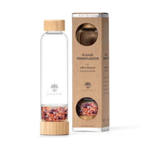 Eine Trinkflasche aus Glas mit Bambus-Applikationen und einem mit Kristallen gefüllten Boden, präsentiert neben ihrer Kartonverpackung.